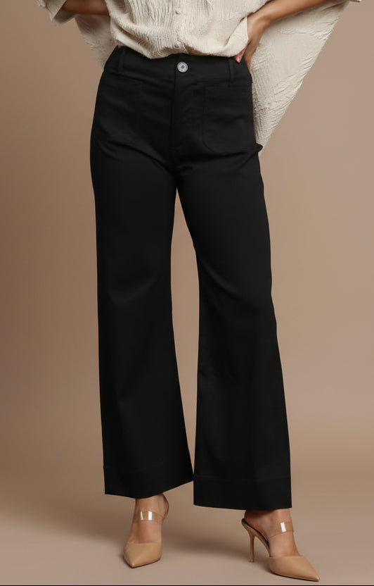 Person wearing black pants and beige shoes on a red background