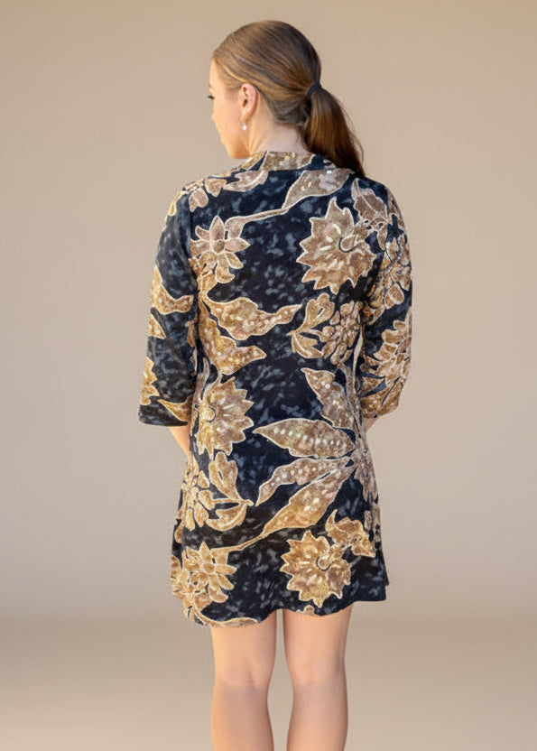 Woman wearing a floral dress standing outside a building.