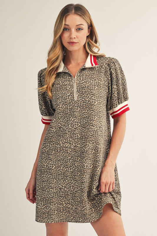 Woman wearing a patterned dress with red and white accents on a plain background