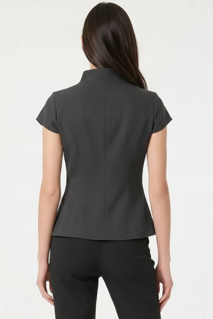 A woman shown from the back wearing a black short-sleeve structured top and black pants against a plain white studio background.
