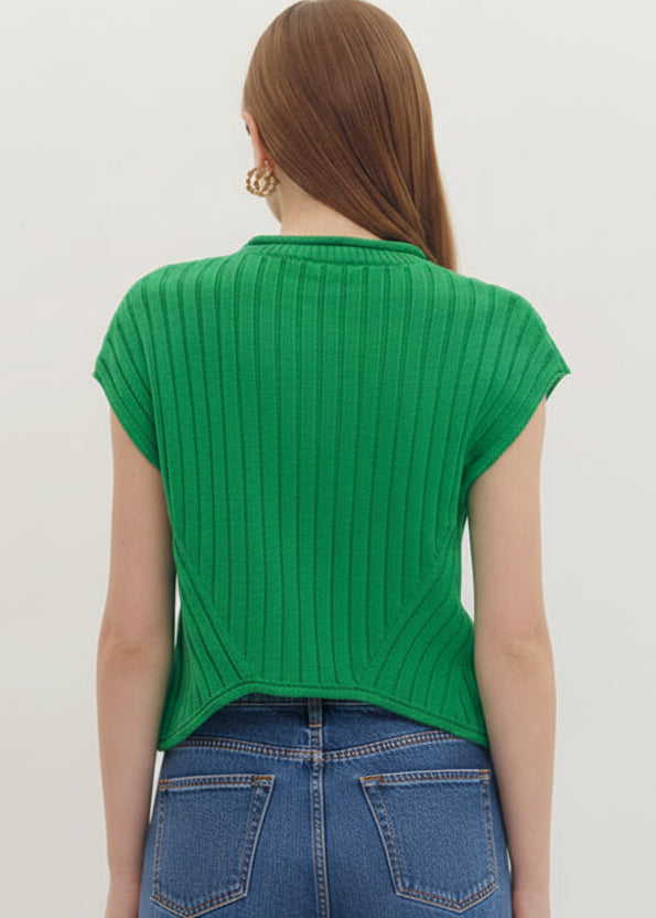 Person wearing a green ribbed top and white shorts on a plain background
