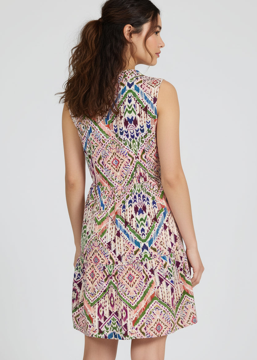Woman wearing a colorful patterned dress on a plain background
