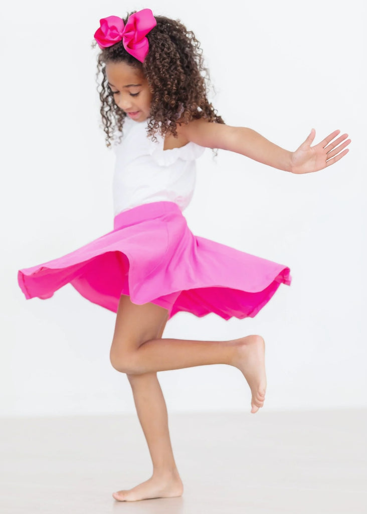 Child wearing a white top and bright pink skirt on a white background