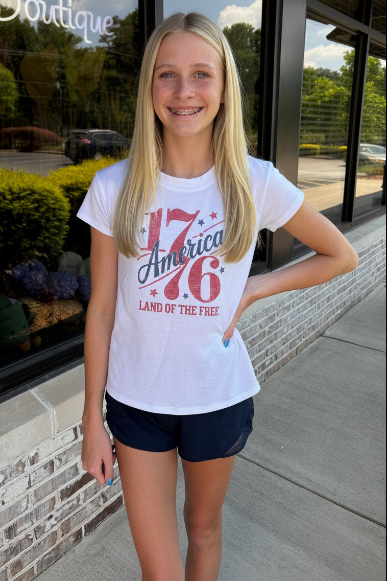 Person wearing a white t-shirt with red text, standing in front of a store entrance.
