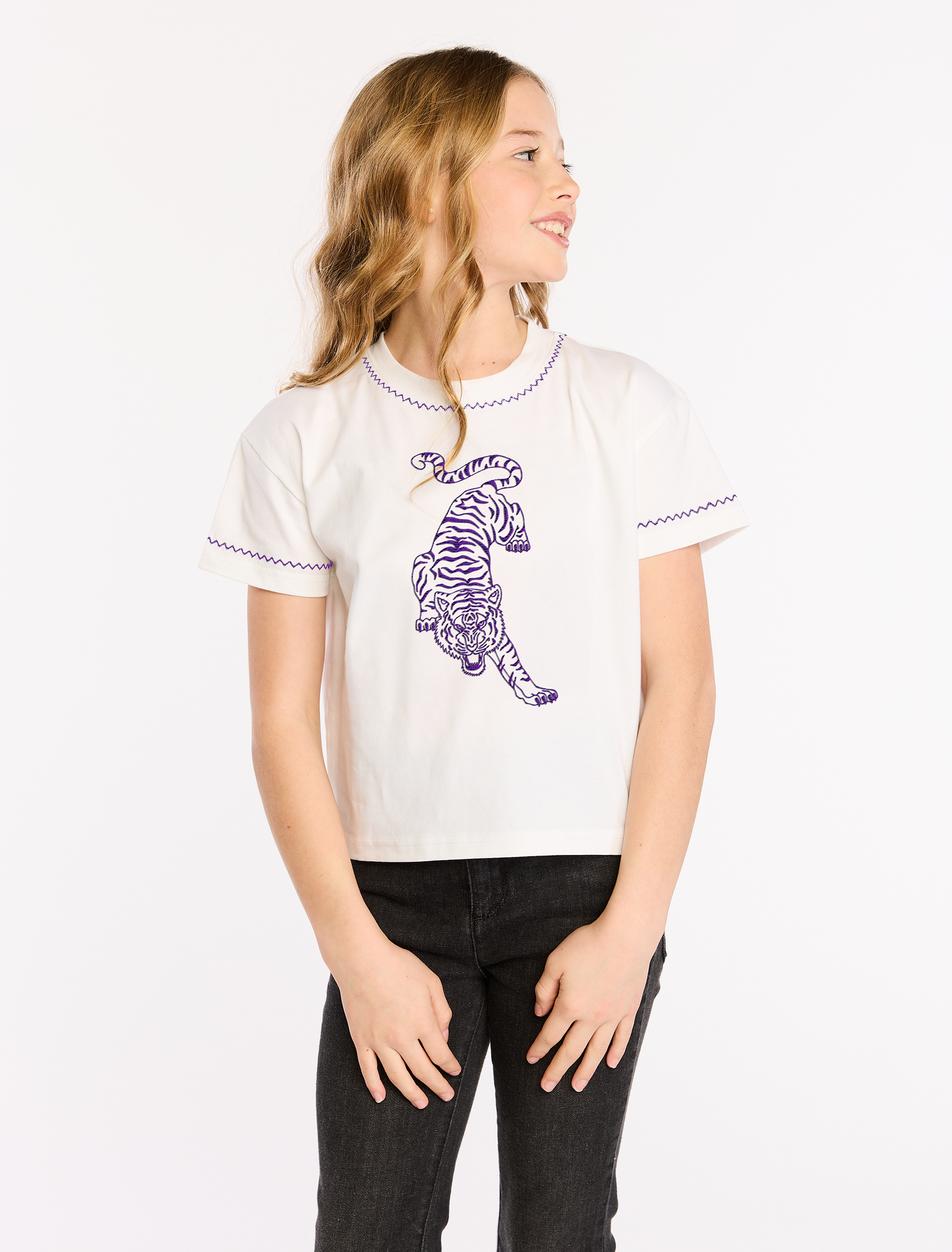 Person wearing a white t-shirt with a purple tiger design on a plain background