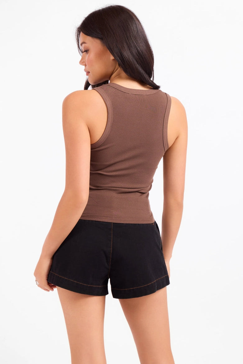 A woman shown from the back wearing a fitted sleeveless brown tank top and black shorts against a plain light background.