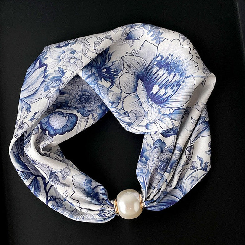 Blue and white floral headband with a pearl on a black box
