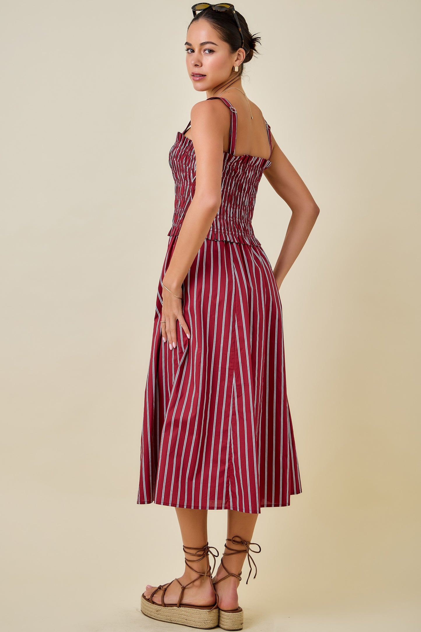 Woman wearing a red and white striped dress on a beige background