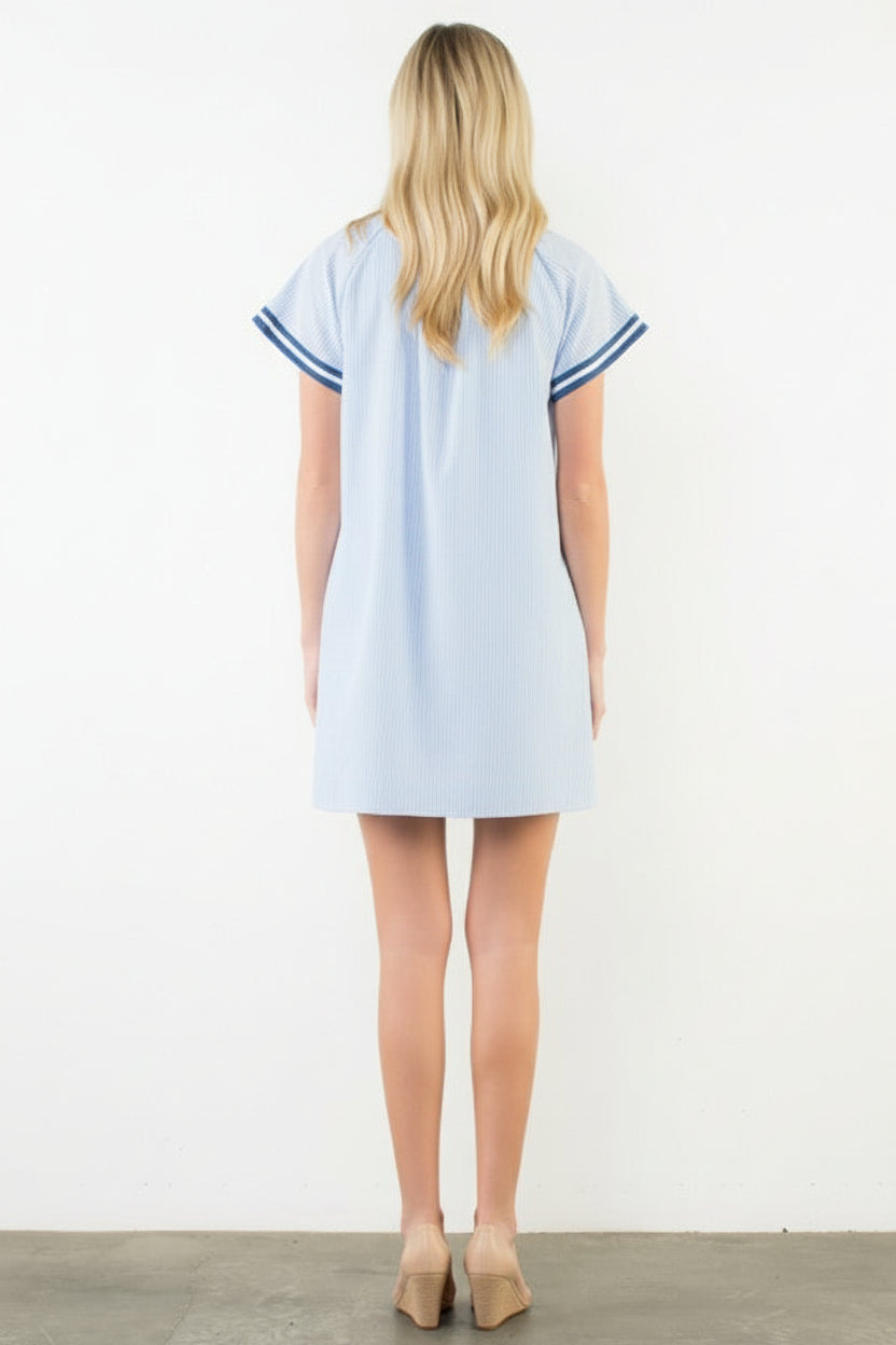 Woman wearing a light blue dress with white trim on a white background