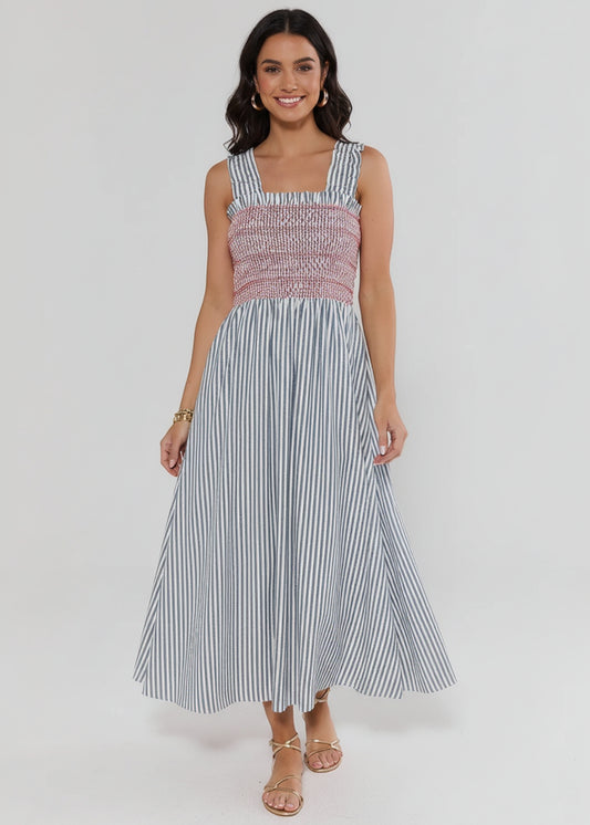 Woman wearing a sleeveless dress with a patterned top and striped skirt on a white background