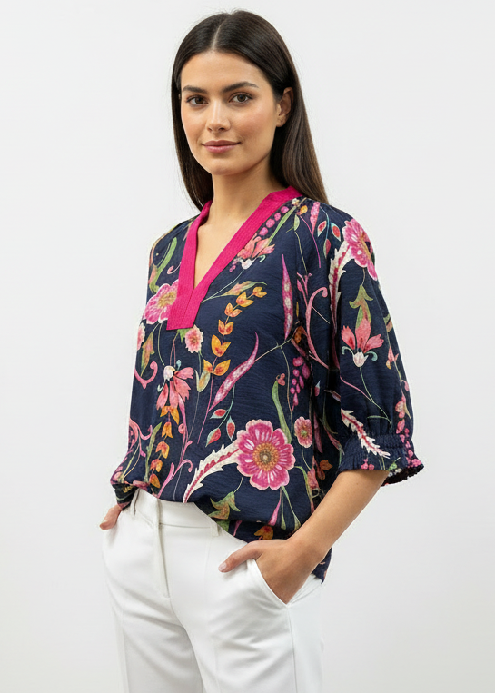 Woman wearing a navy floral blouse with pink accents on a white background