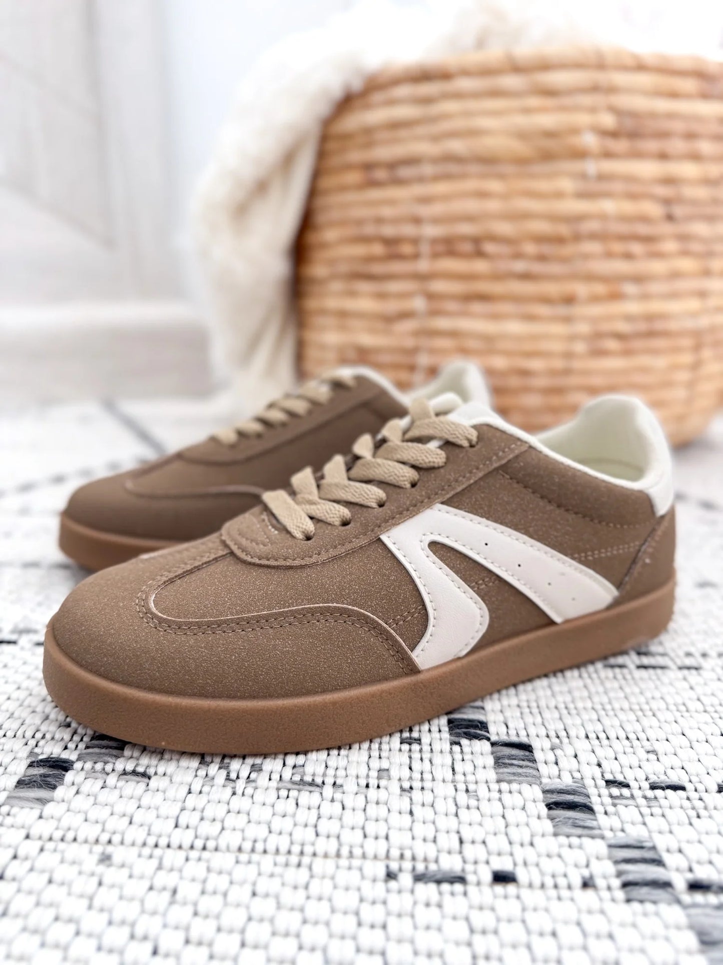 Brown sneakers with white stripes on a woven surface