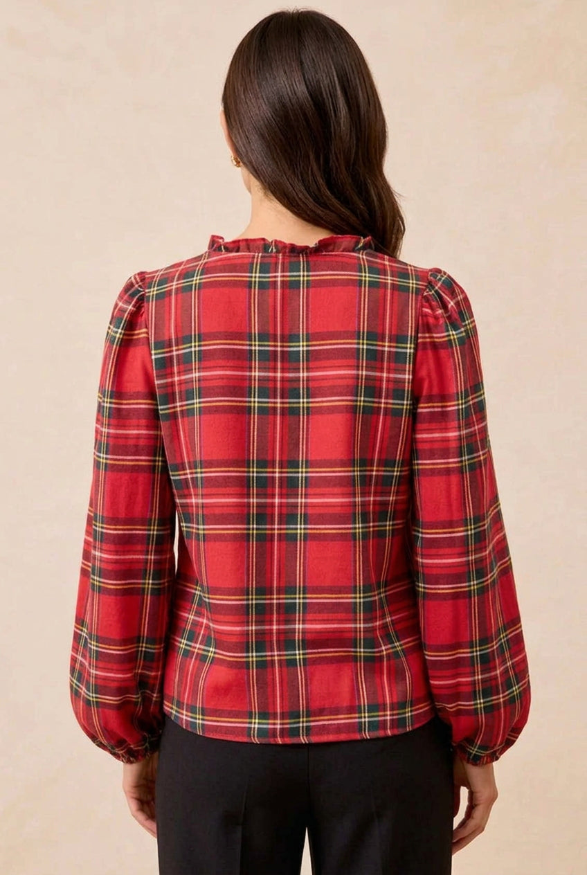Woman wearing a red plaid blouse with puff sleeves against a beige background