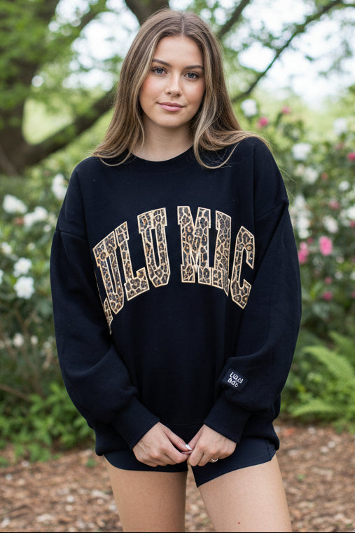 Navy blue sweatshirt with leopard print text worn by a person on a white background