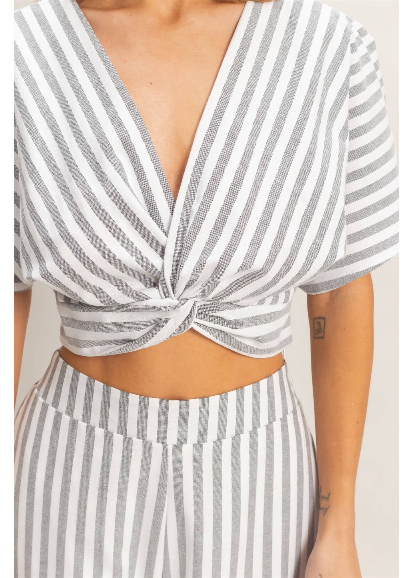 Striped crop top with a knot detail on a plain background