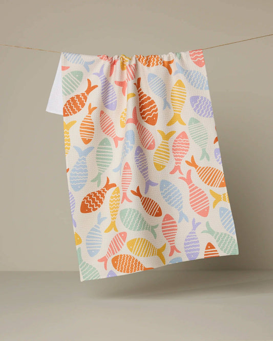 Colorful fish-patterned towel hanging on a line against a neutral background