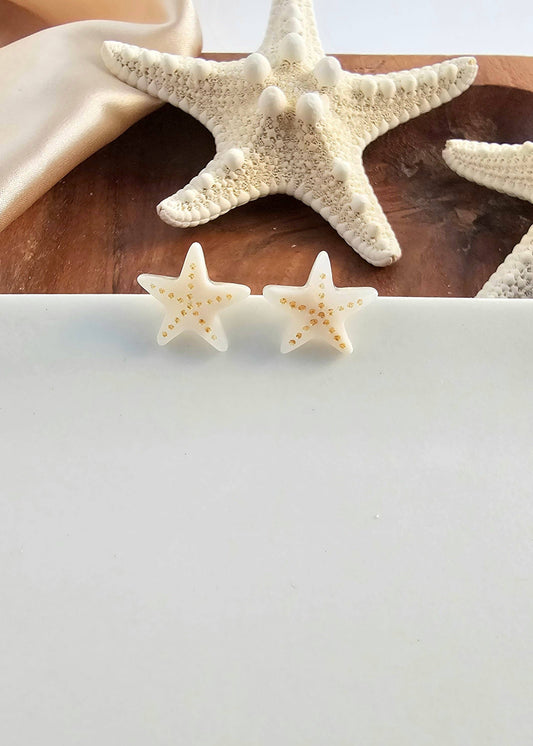 Starfish earrings displayed on a white background with starfish and shells in the background.