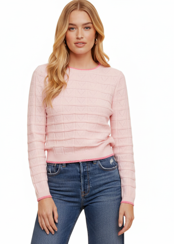 Woman wearing a pink textured sweater and blue jeans on a white background
