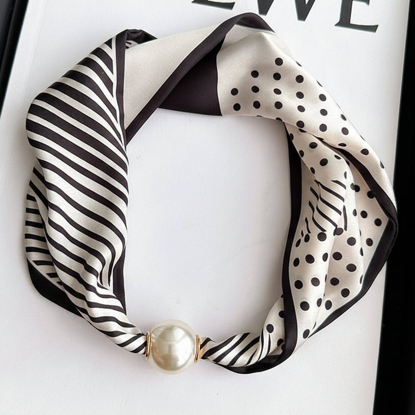 Black and white patterned scarf with a pearl necklace on a LOEWE branded background