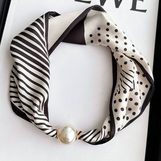 Black and white patterned scarf with a pearl necklace on a LOEWE branded background