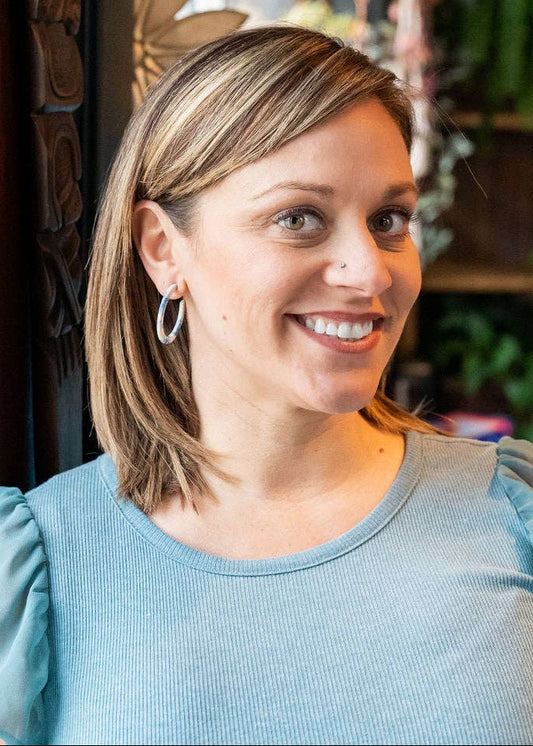 Woman with a smile in a casual setting with plants and decor