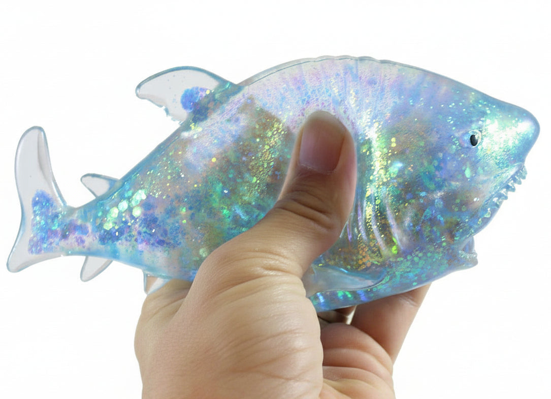 Hand holding a glittery fish-shaped toy with a white background