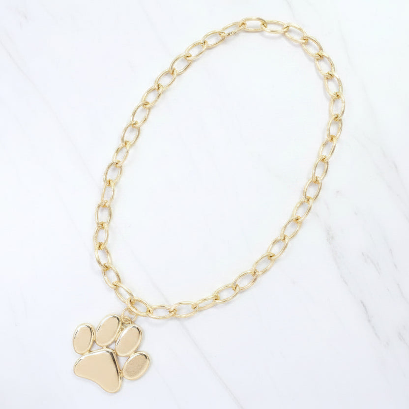 Gold beaded necklace with a paw charm on a white background