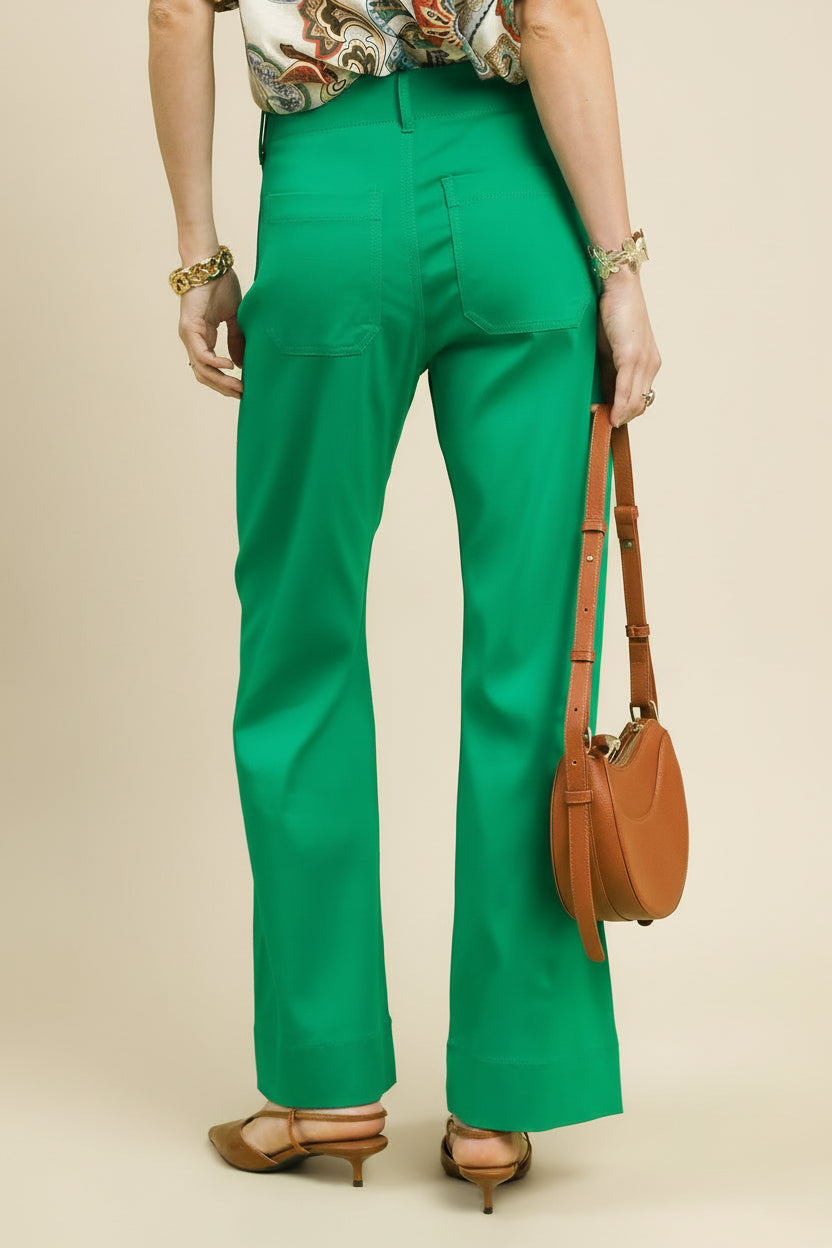 Person wearing green pants holding a brown bag on a light green background