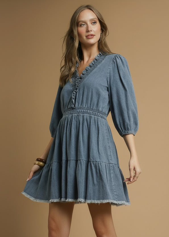 Woman wearing a light denim dress with puffed sleeves on a brown background