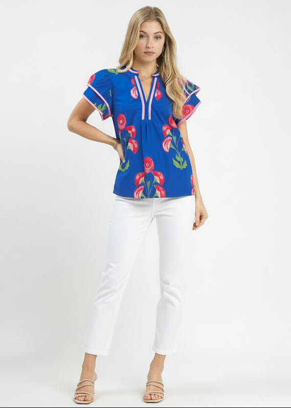 Woman wearing a blue floral blouse and beige pants on a white background