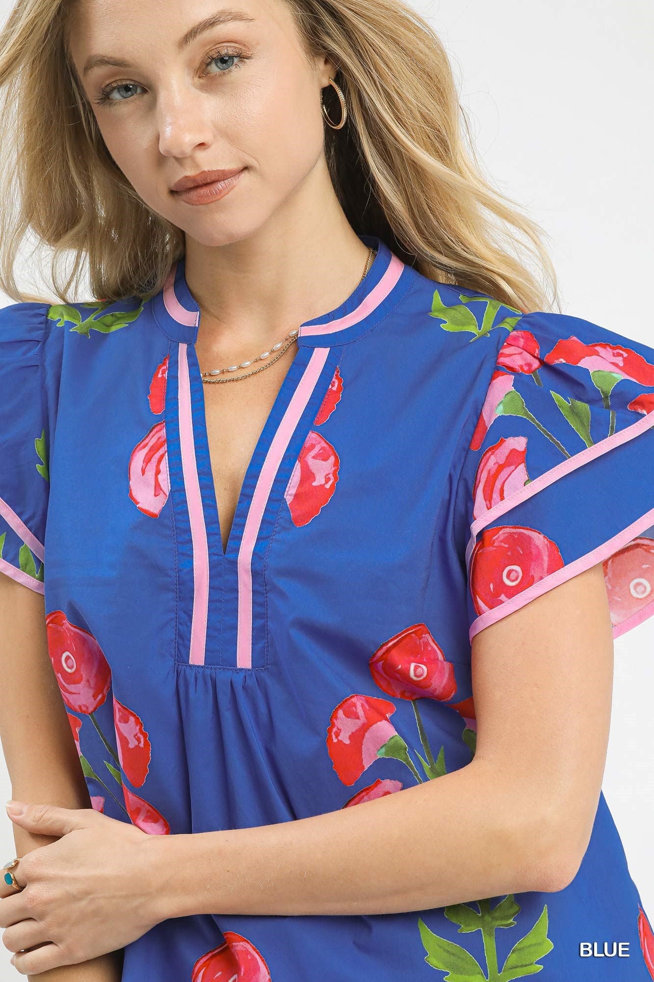 Woman wearing a blue dress with red floral patterns on a white background