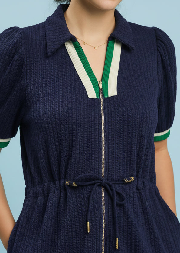 Navy dress with green and white trim on a light blue background