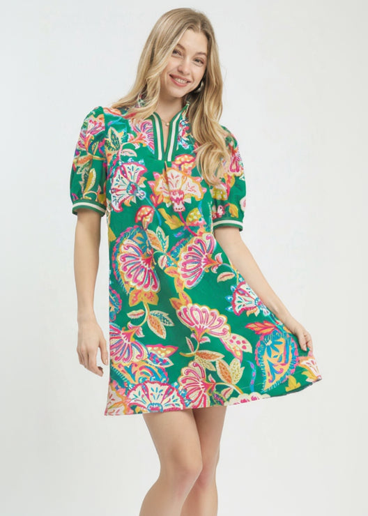 Woman wearing a colorful floral dress with 'UMgee Exclusive' branding on a white background