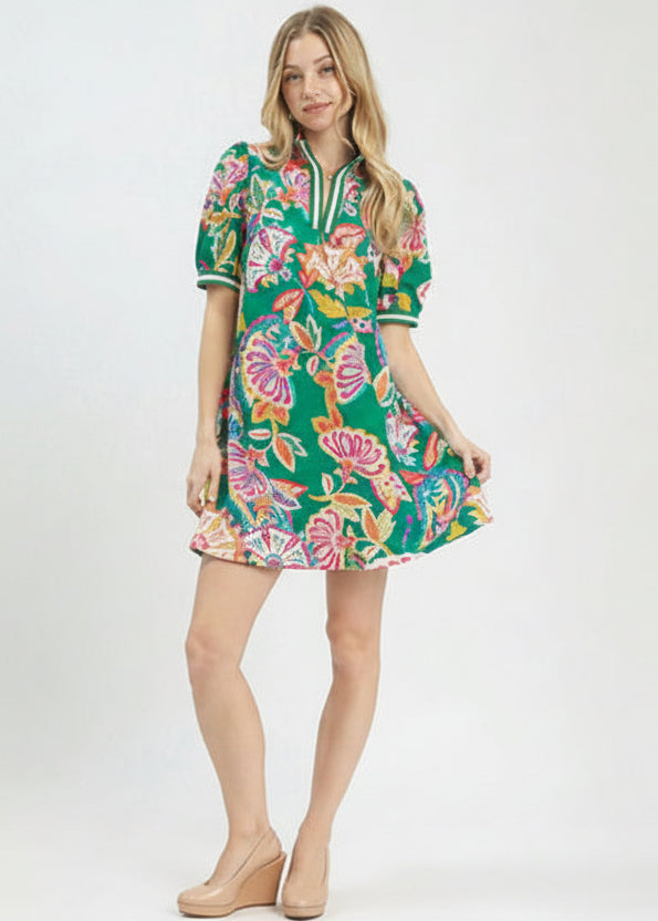Woman wearing a colorful floral dress on a white background with Umgee branding.