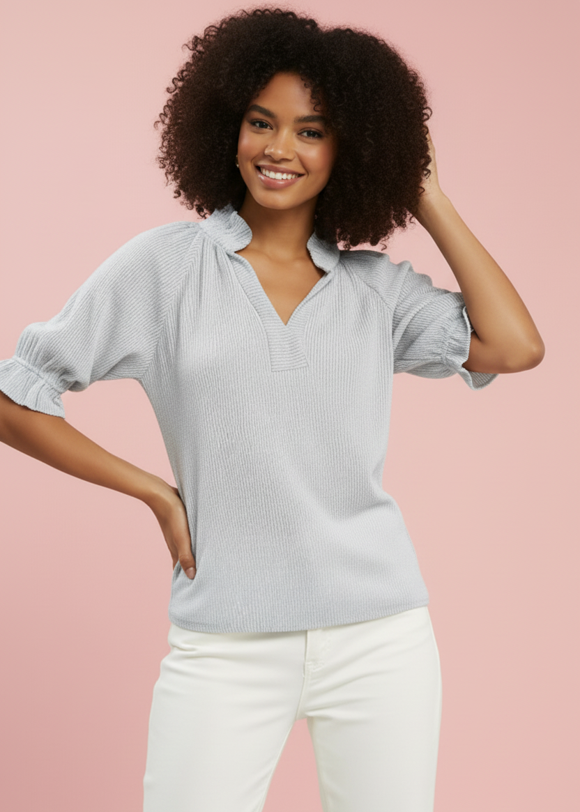Woman wearing a light blue blouse with ruffled sleeves against a pink background
