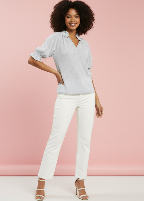 Woman wearing a light blue blouse and white pants against a pink background