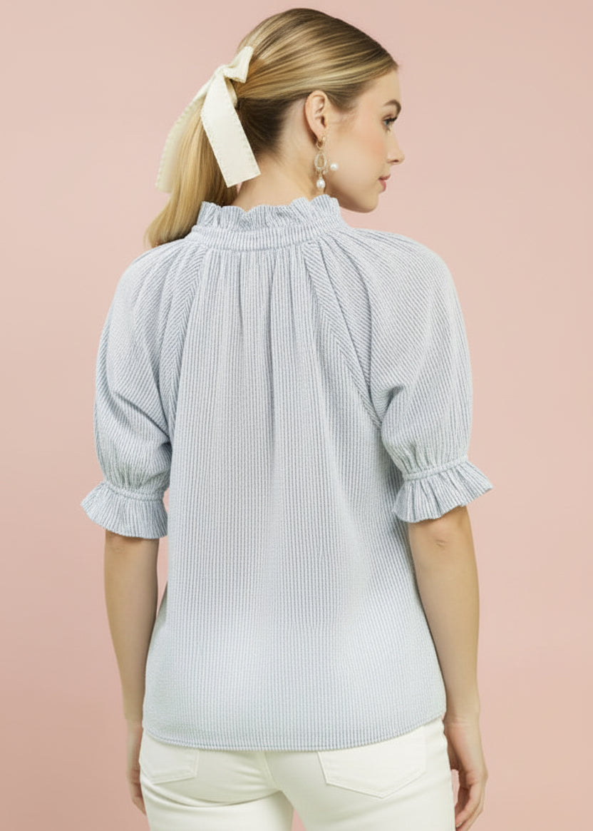 Woman wearing a light blue checkered blouse and blue striped pants on a green background