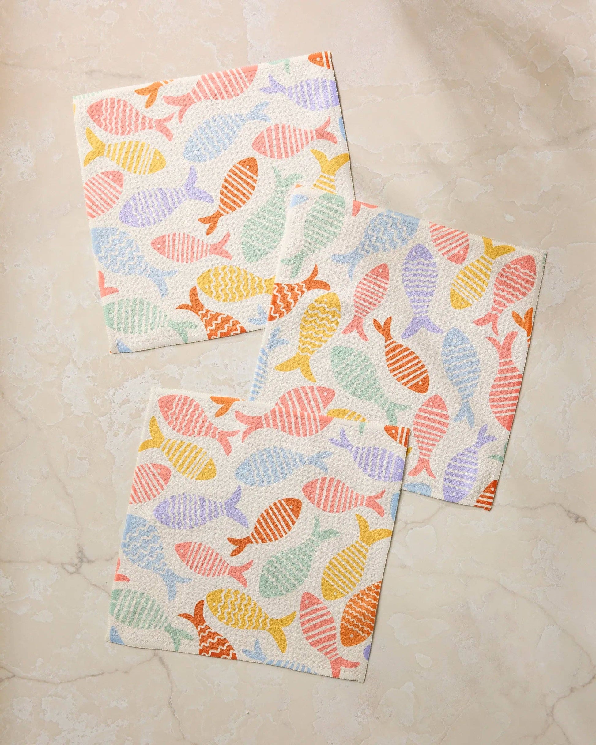 Two colorful fish-patterned towels on a marble surface