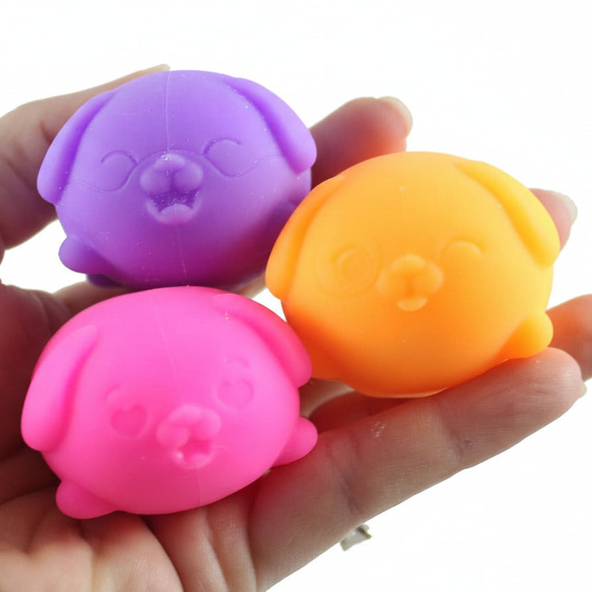 Three colorful dog-shaped toys held in a hand with 'Curious Minds' branding.