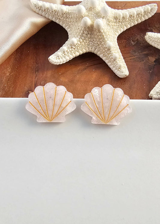 Shell-shaped earrings with gold accents on a white background, with starfish in the background.