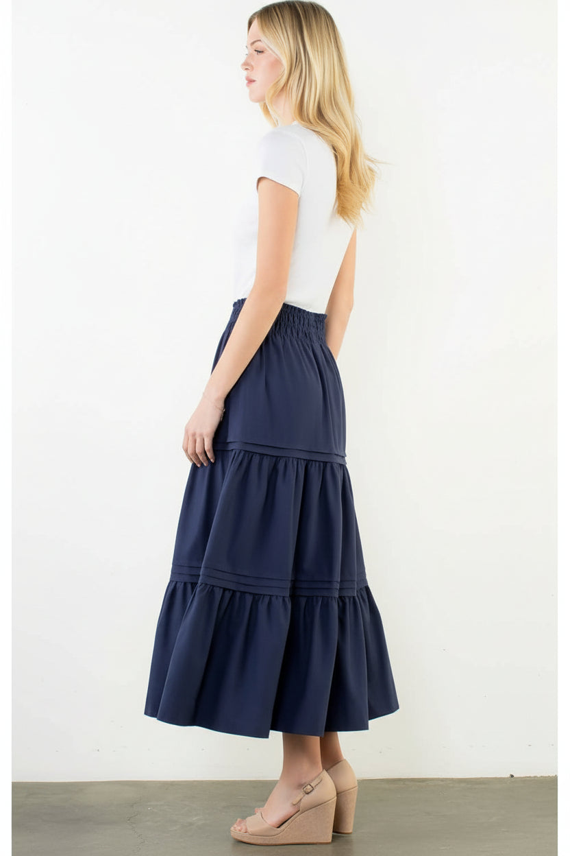 Woman wearing a navy tiered skirt on a white background