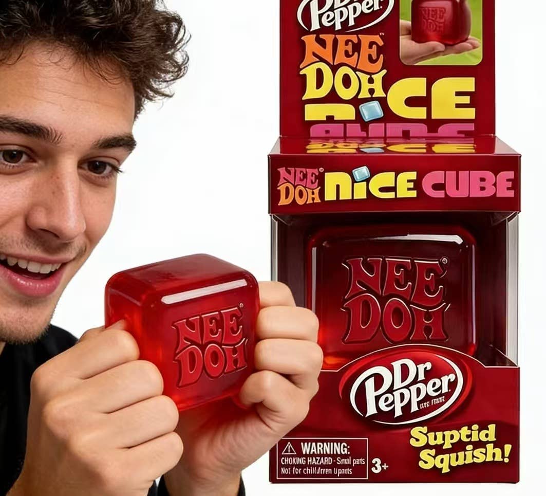 Person holding a red 'Nee Doh' cube with Dr Pepper branding against a white background
