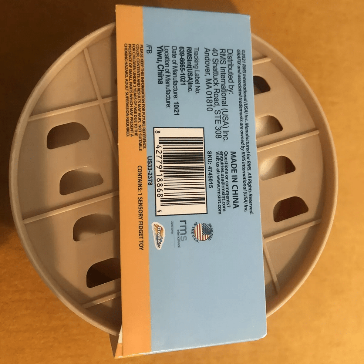 Back of a container with a label showing branding and product details on a brown background