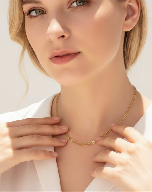 Gold necklace on a person wearing a white top