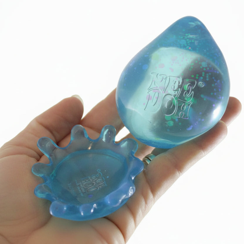 Blue plastic toy with a teardrop shape held in a hand, branded 'Curious Minds Busy Bags'.
