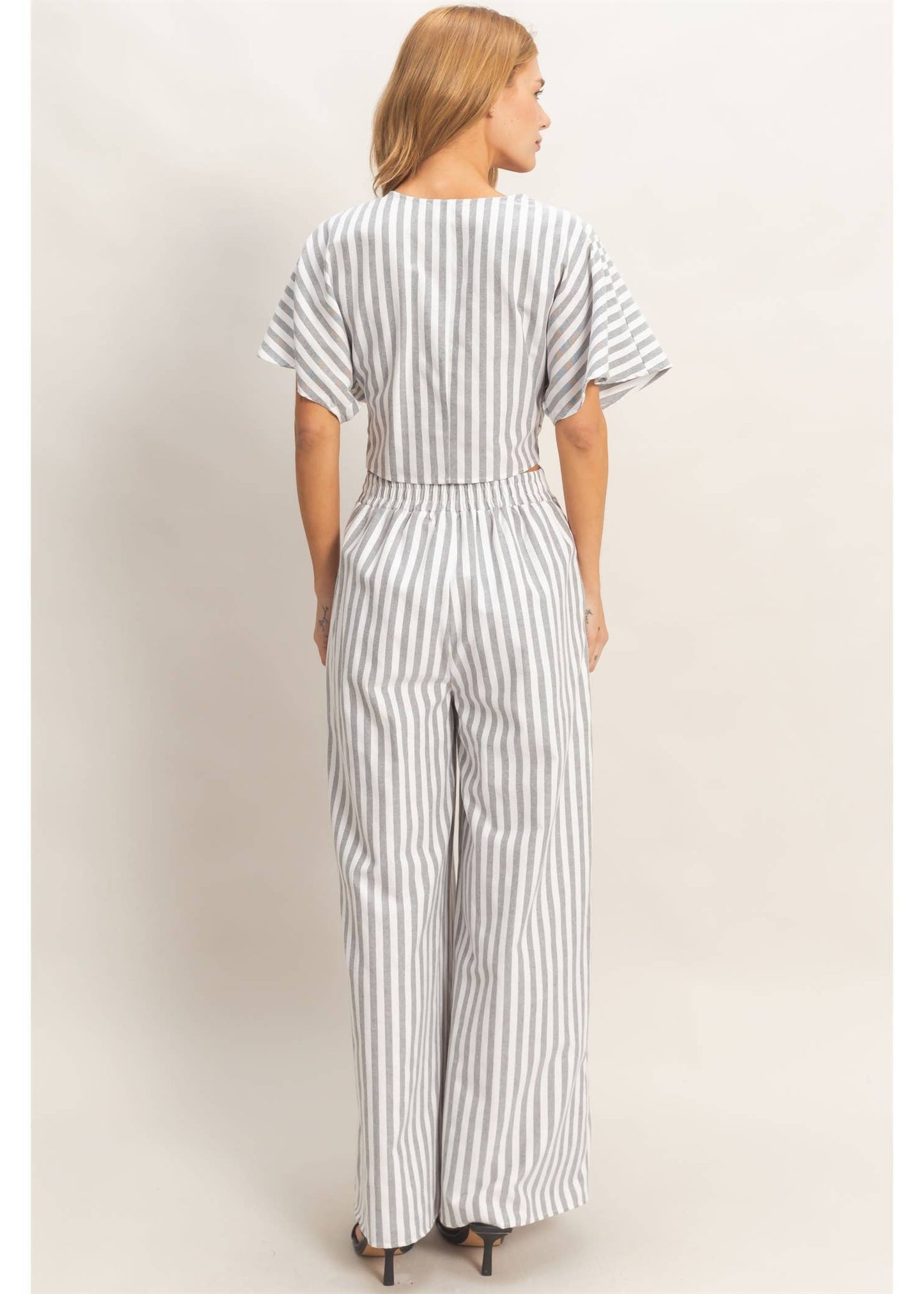 Woman wearing a striped jumpsuit against a plain background