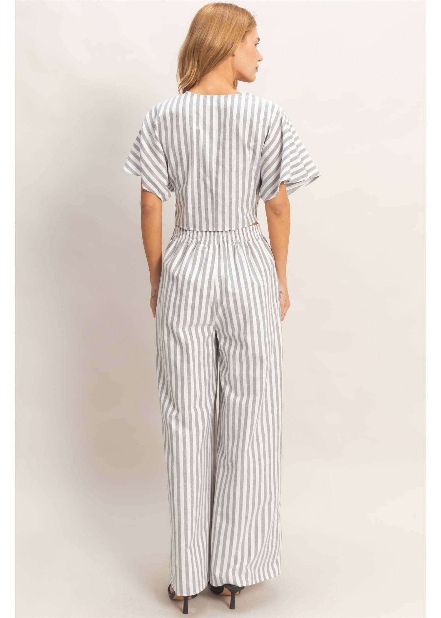 Woman wearing a striped jumpsuit against a plain background