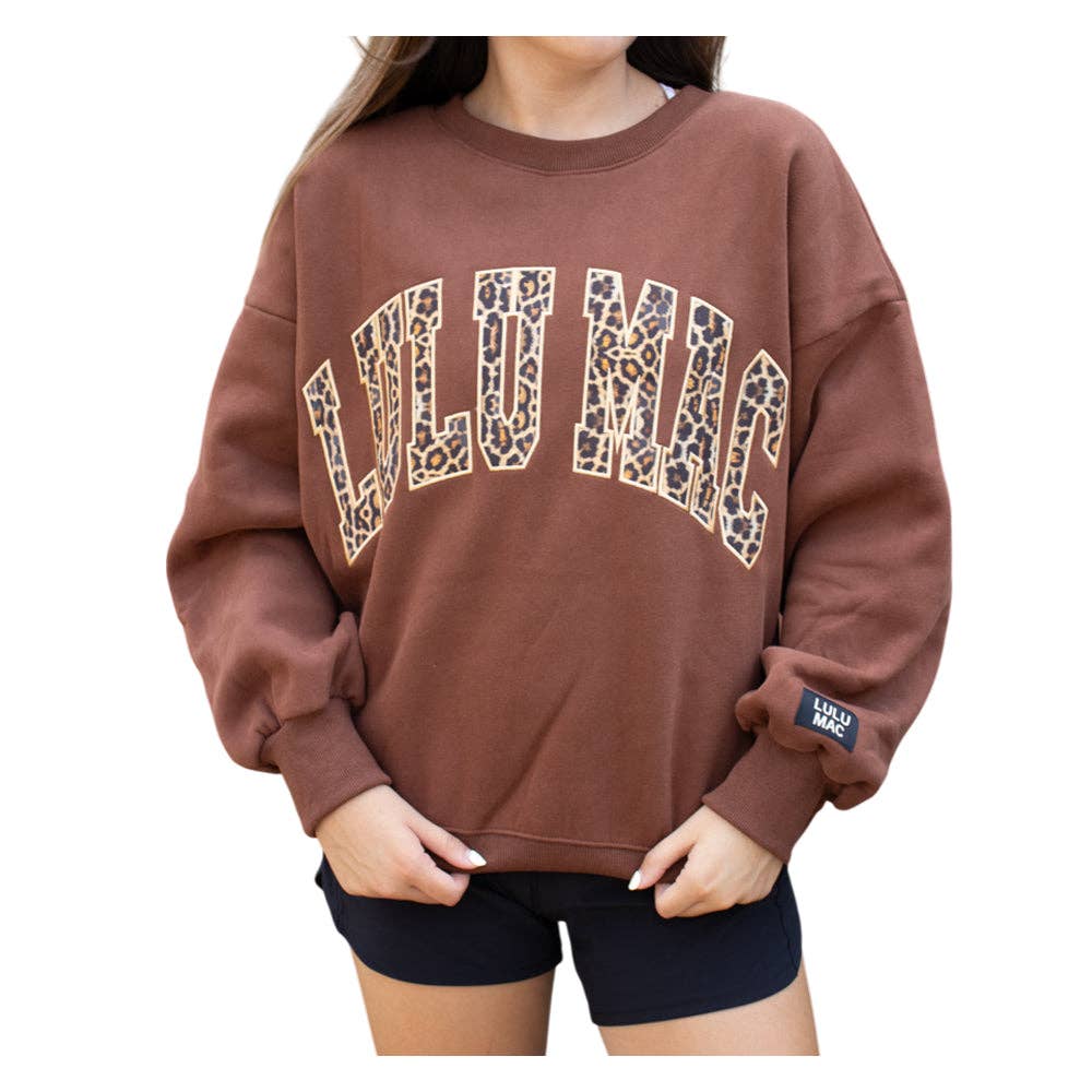 Brown sweatshirt with leopard print text worn by a person on a white background