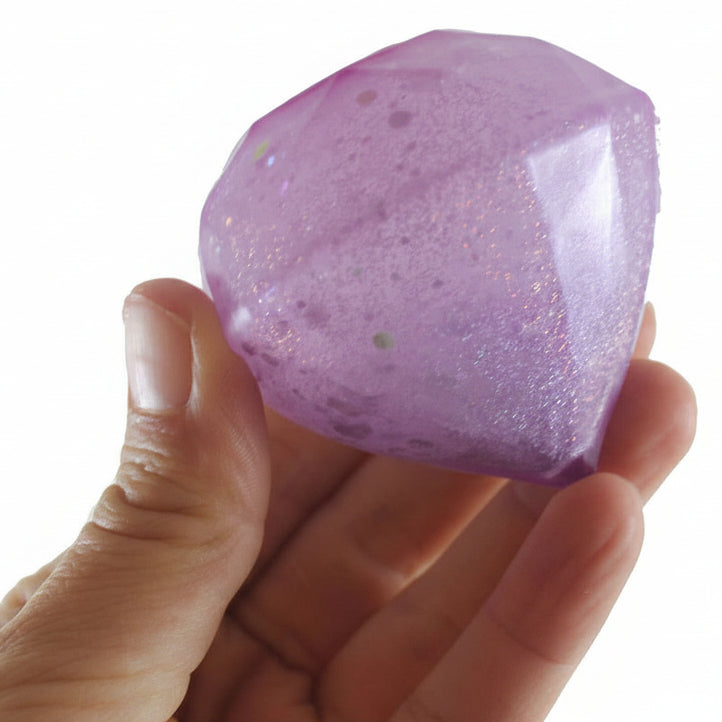 Hand holding a purple glittery crystal with 'Curious Minds' logo in the corner