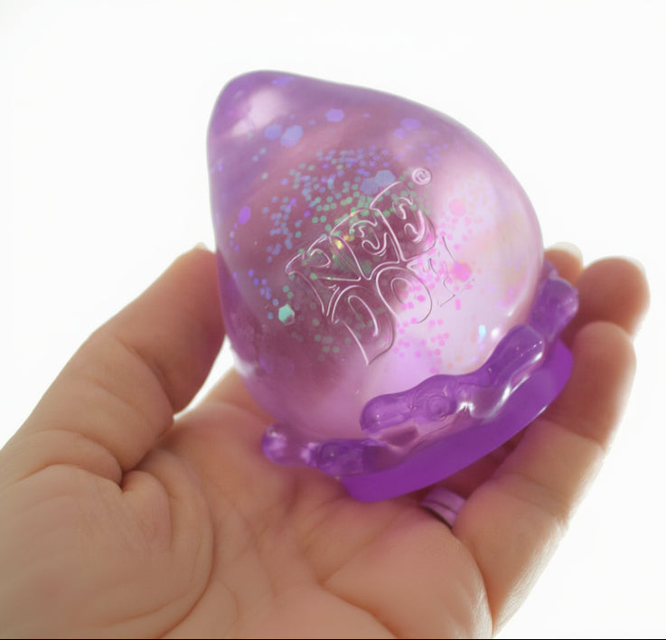 Purple and pink textured ball held in a hand with 'Curious Minds' branding.